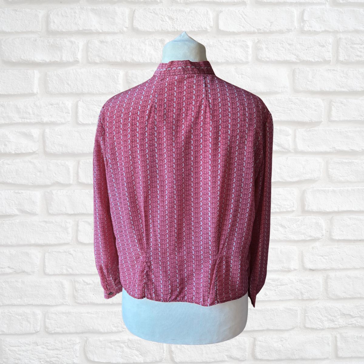 Pink patterned shirt on a mannequin against a white brick wall background