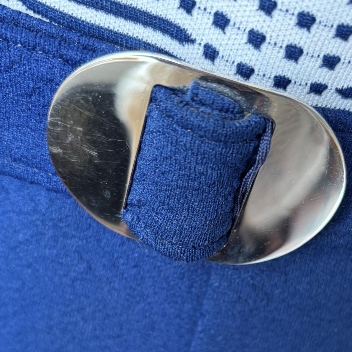 Close-up of a blue sock with a metal button on a blue fabric background