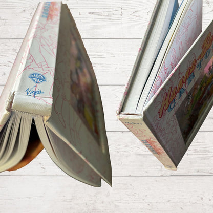 Open books with colorful text and illustrations on a light wooden surface