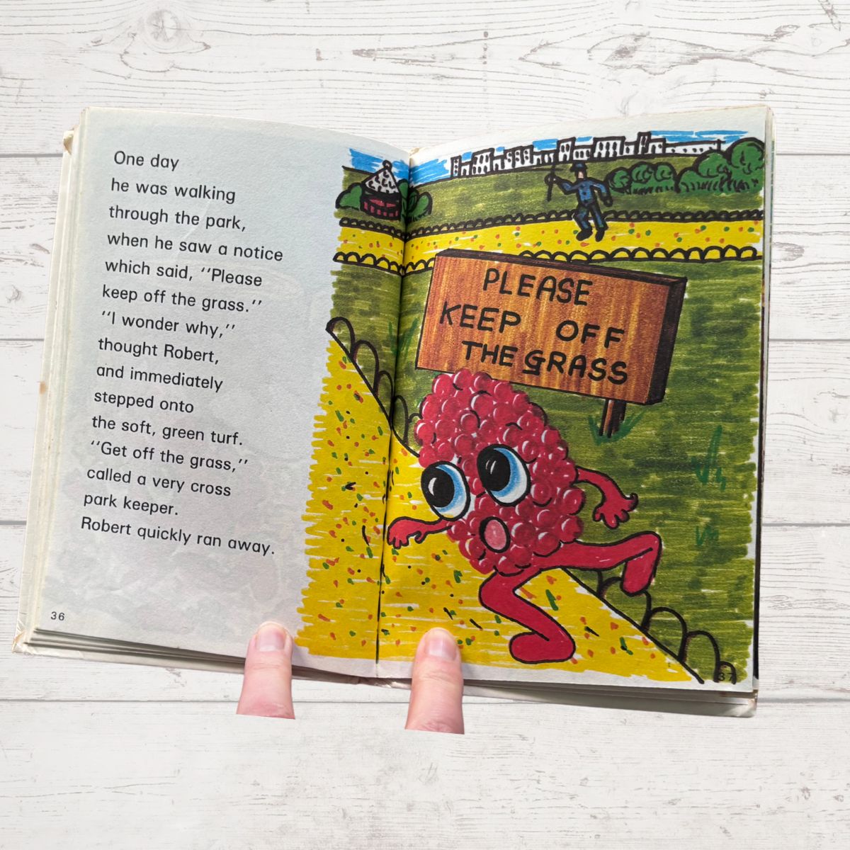 Open book with cartoon character and 'Please Keep Off the Grass' sign