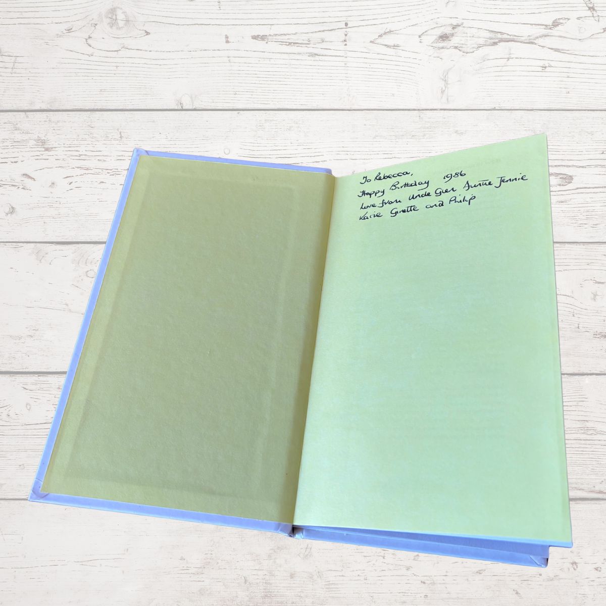 Open book with green pages on a light wooden surface