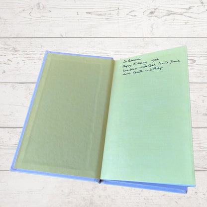 Open book with green pages on a light wooden surface