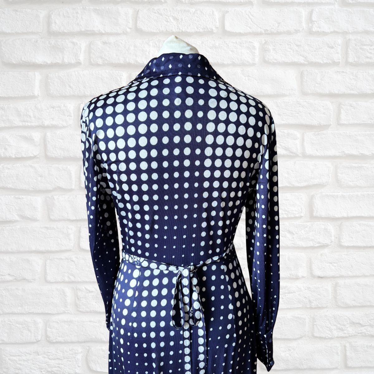 Back of dark blue and white polka dot dress on a white background 