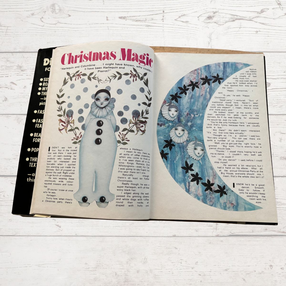 Open book with Christmas-themed illustrations on a white wooden surface
