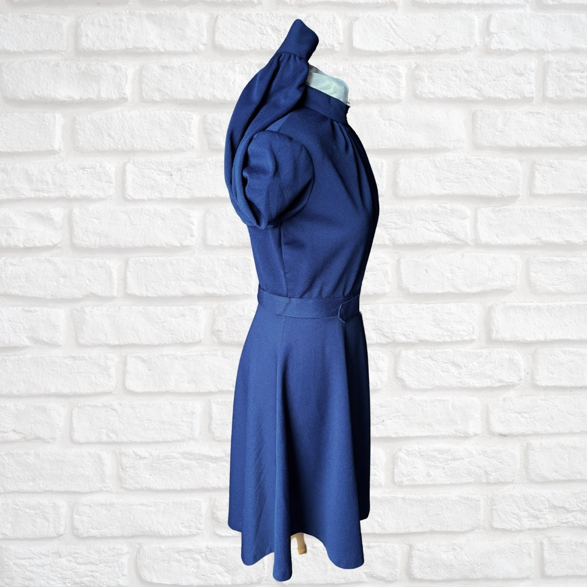 Blue dress on a mannequin against a white brick wall background