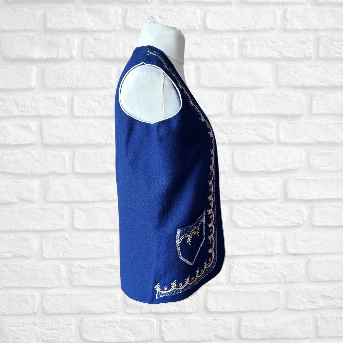 Blue waistcoat with embroidery on a white brick wall background