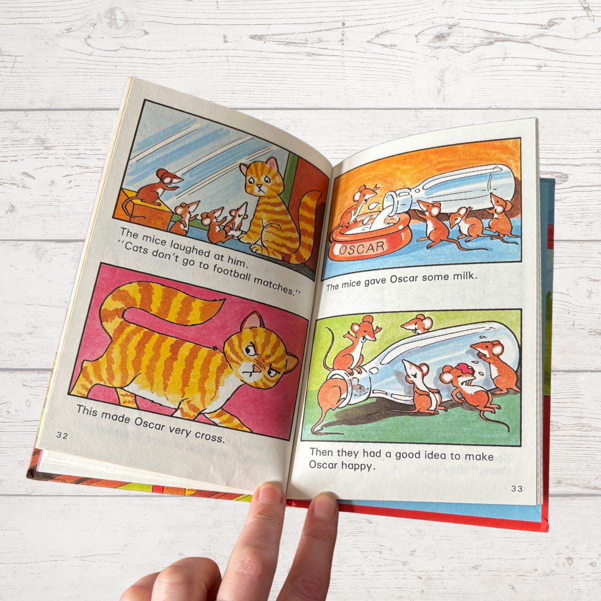 Open book with colorful illustrations of a cat and mice on a wooden surface