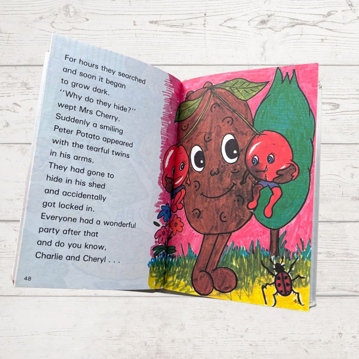 Open children's book with a cartoon potato character and red vegetables on a wooden surface
