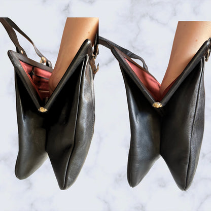 Black leather handbag held by a person against a marble background