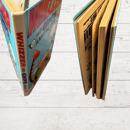Two open books titled 'Whizzer and Chips Annual' on a light wooden surface.