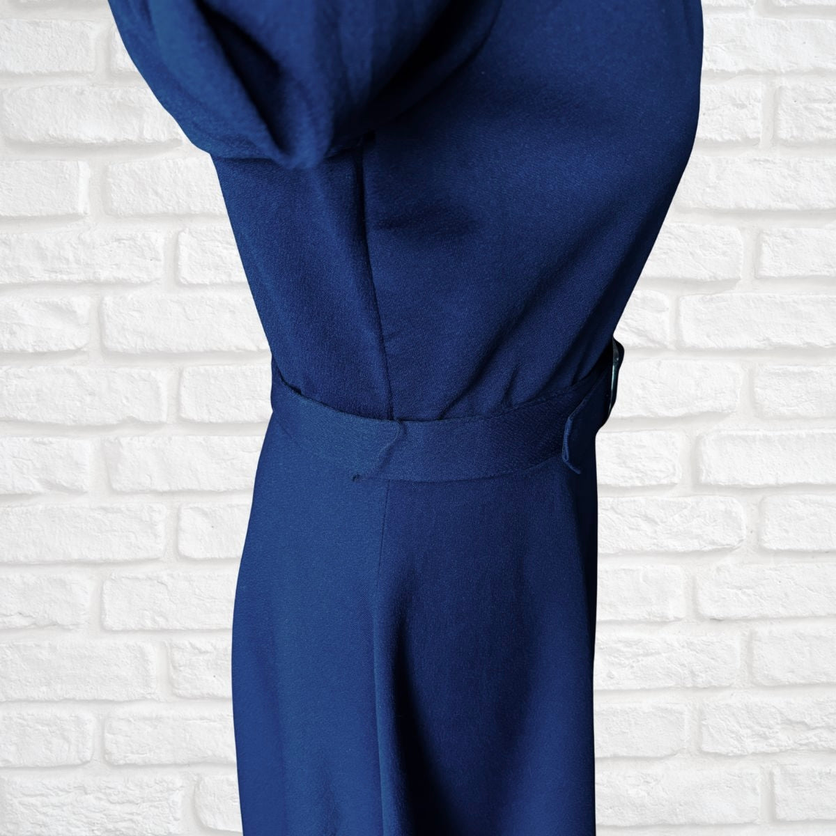 Navy blue dress against a white brick wall background