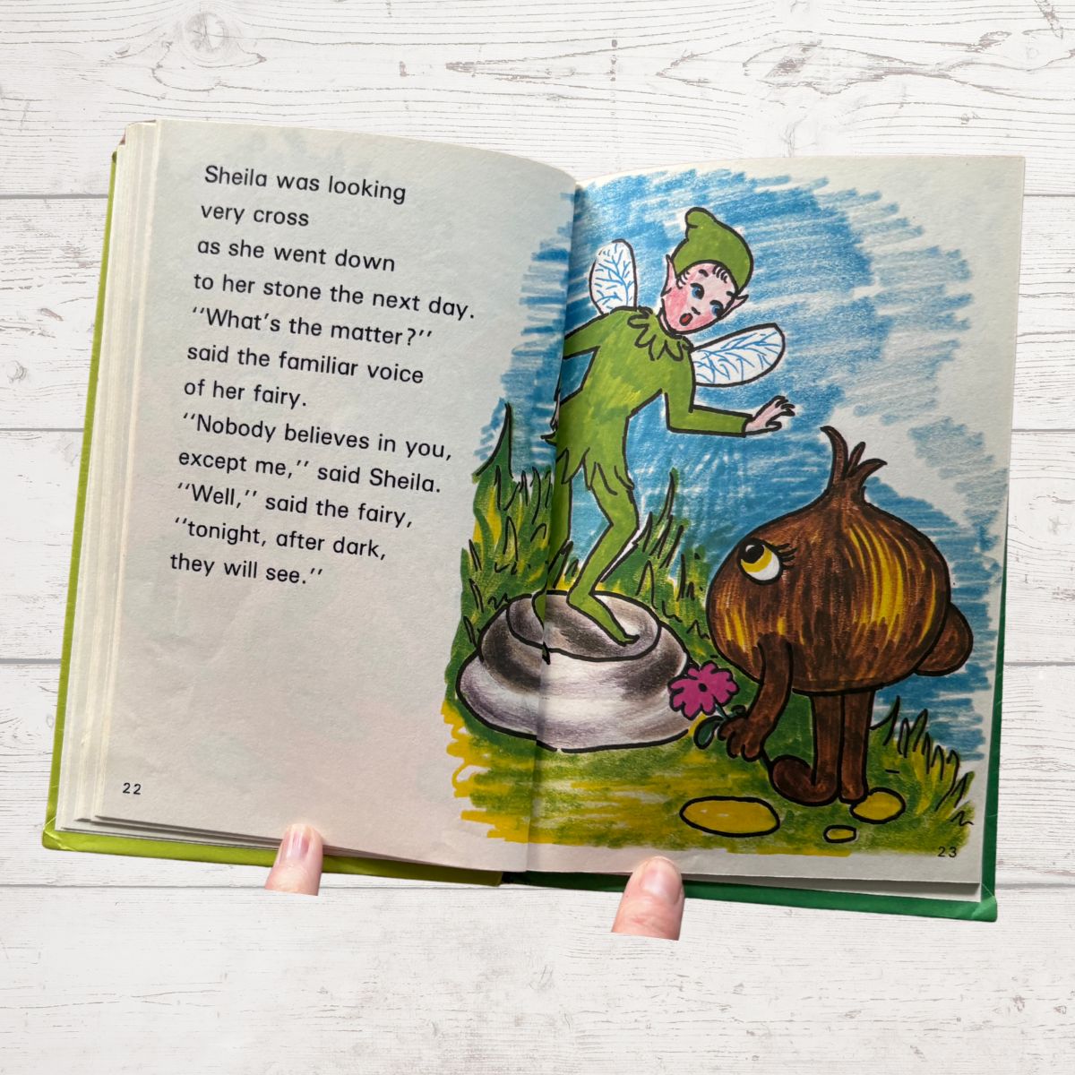 Open book with a fairy and onion character on a wooden surface