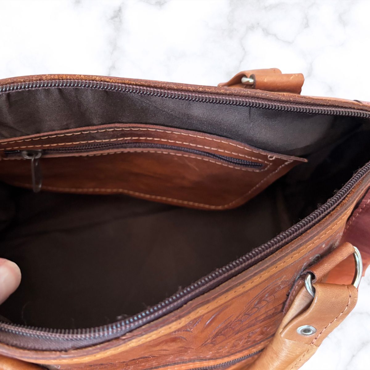 Brown leather bag with open interior on a white background
