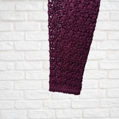 Close-up of a burgundy  textured fabric against a white brick wall background