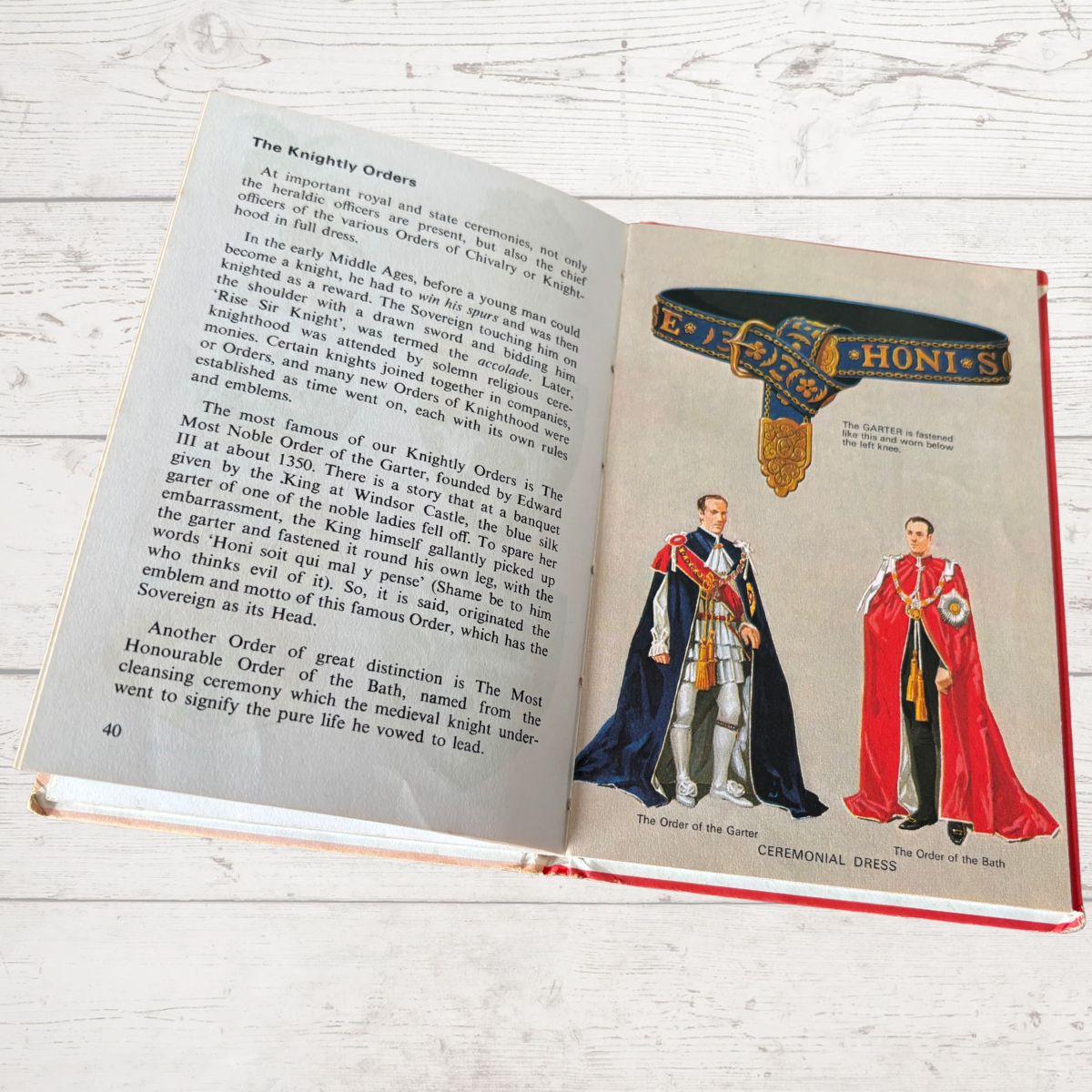 Open book showing illustrations of ceremonial dress and text on a wooden surface