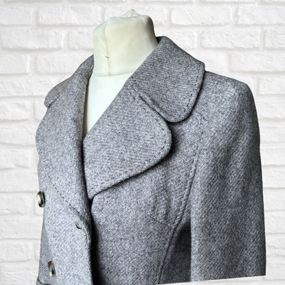 Gray coat on a mannequin against a white brick wall background
