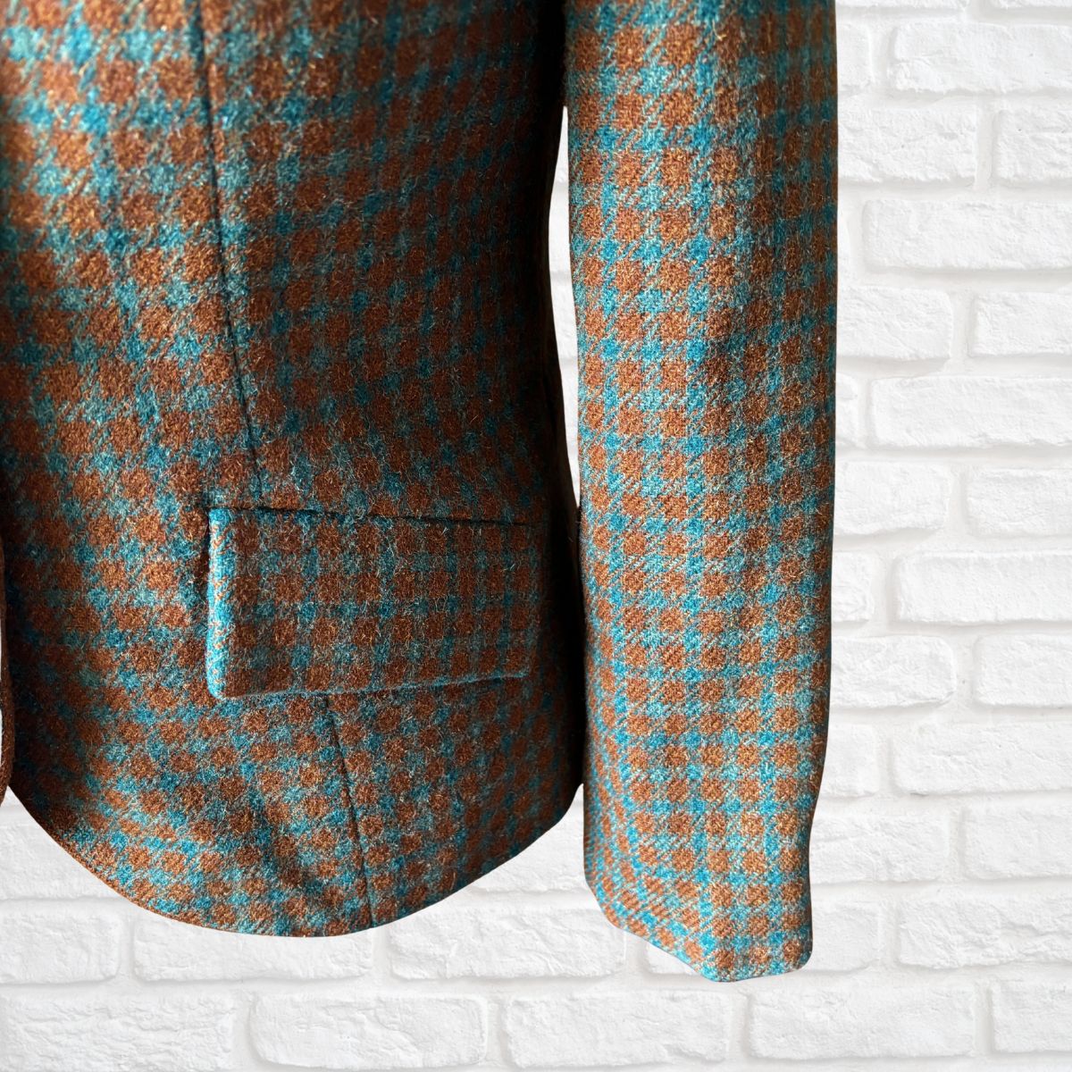 Plaid jacket with brown and blue pattern on a white brick wall background