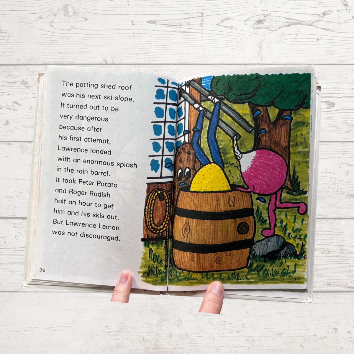 Open book with colorful illustration of a potting shed and characters on a wooden surface