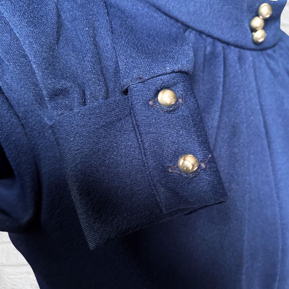 Close-up of a blue cuff with silver  buttons on a wooden surface