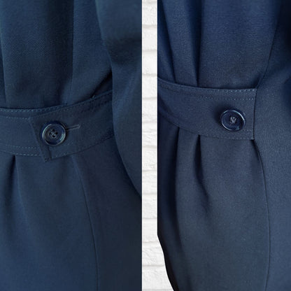 Close-up of a navy blue coat with a button detail on a white background