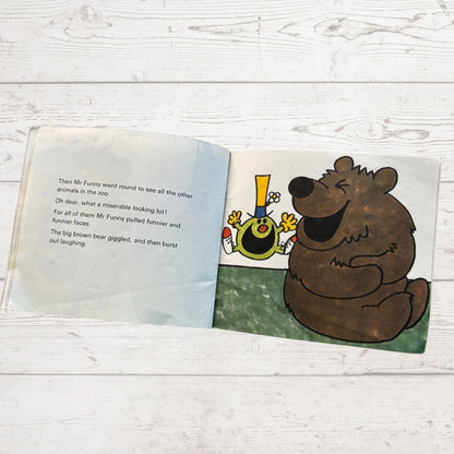 Open children's book with a cartoon bear and other characters on a wooden surface