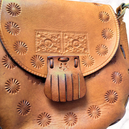 Brown leather bag with embossed patterns on a white background