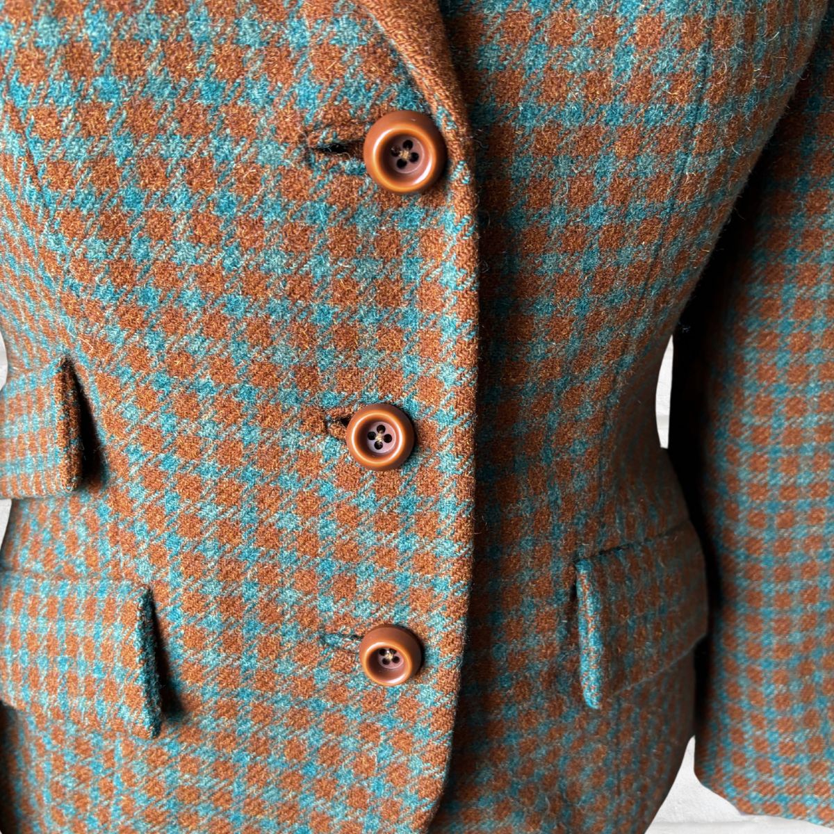 Close-up of a checkered suit jacket with brown buttons on a white background