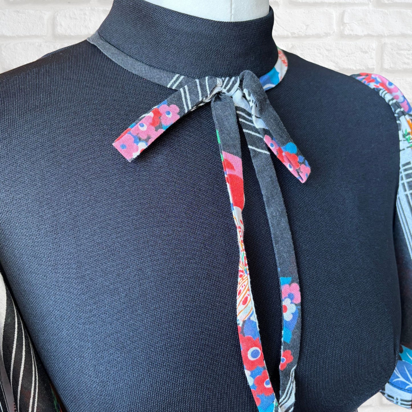 Close up of black bodice with floral  tie at the high neck
