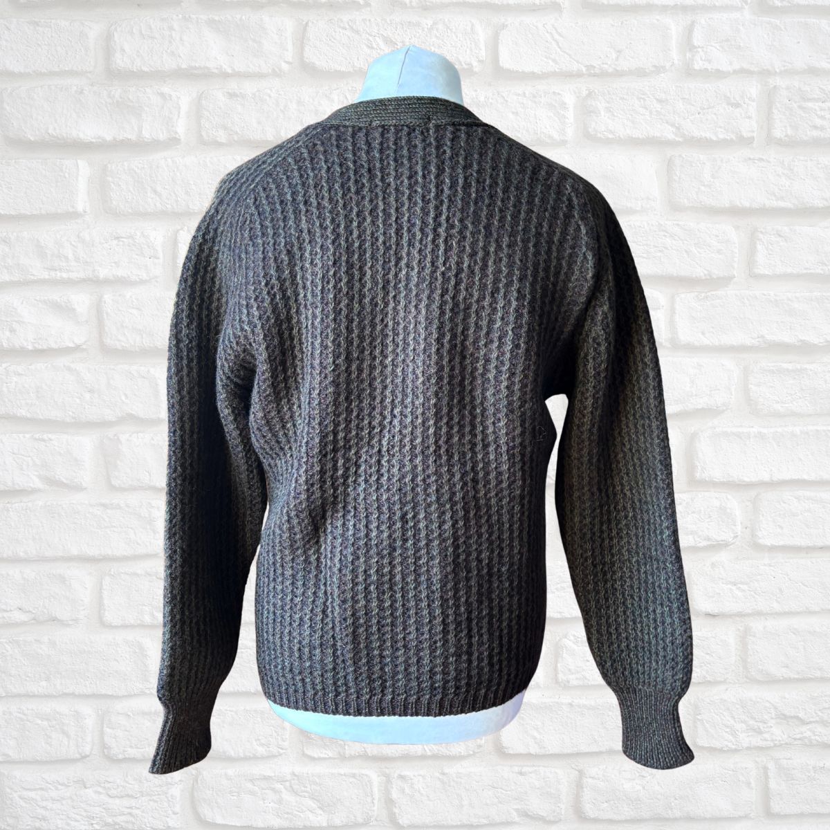 Dark brown  knitted sweater on a mannequin against a white brick wall background