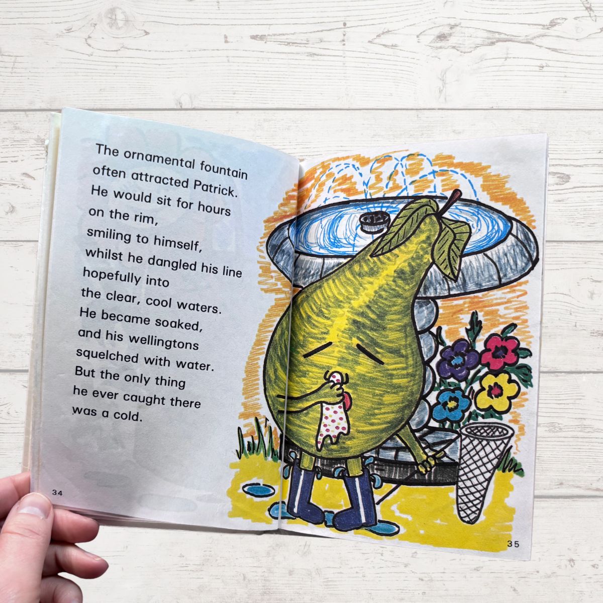 Open book with a colorful illustration of a pear character near a fountain on a wooden surface.