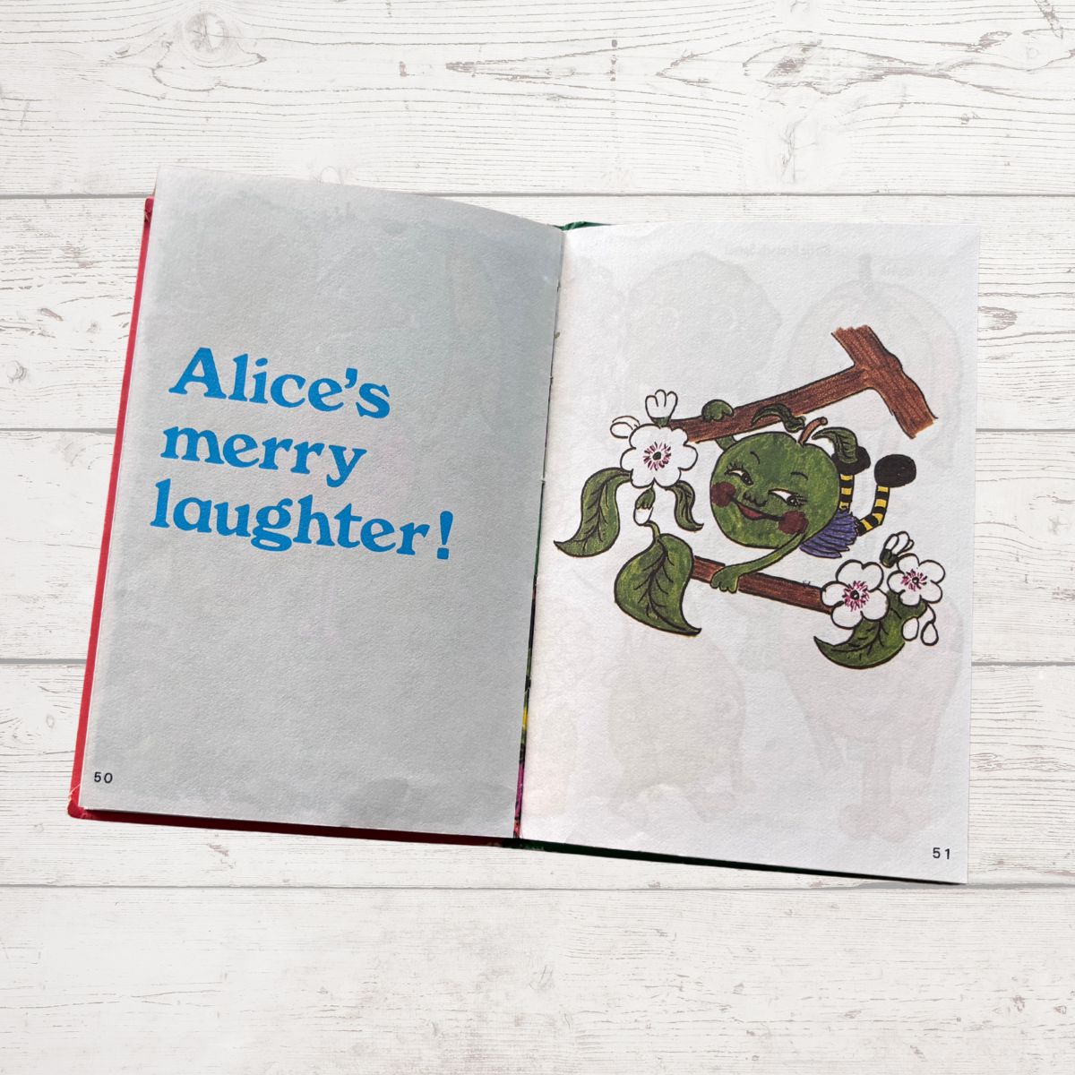Open book with illustration of a green character and text on a wooden surface