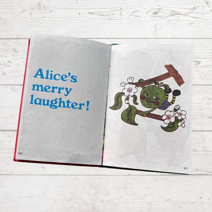 Open book with illustration of a green character and text on a wooden surface