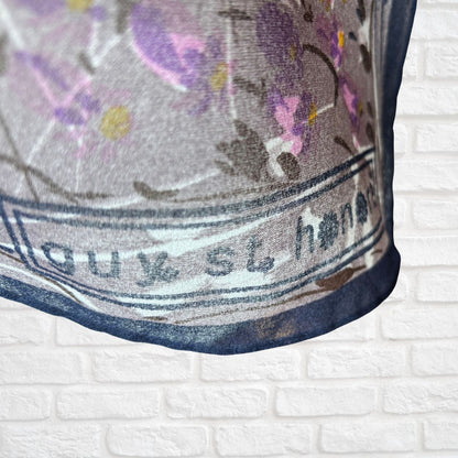 Close-up of a fabric with floral patterns and text on a white brick background