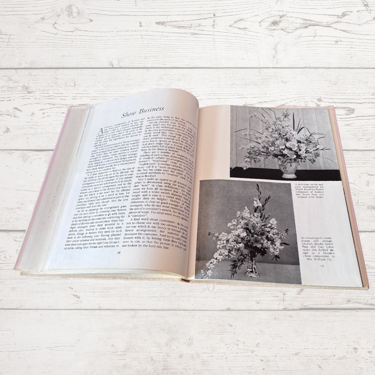 Open book with black and white photos of floral arrangements on a wooden surface