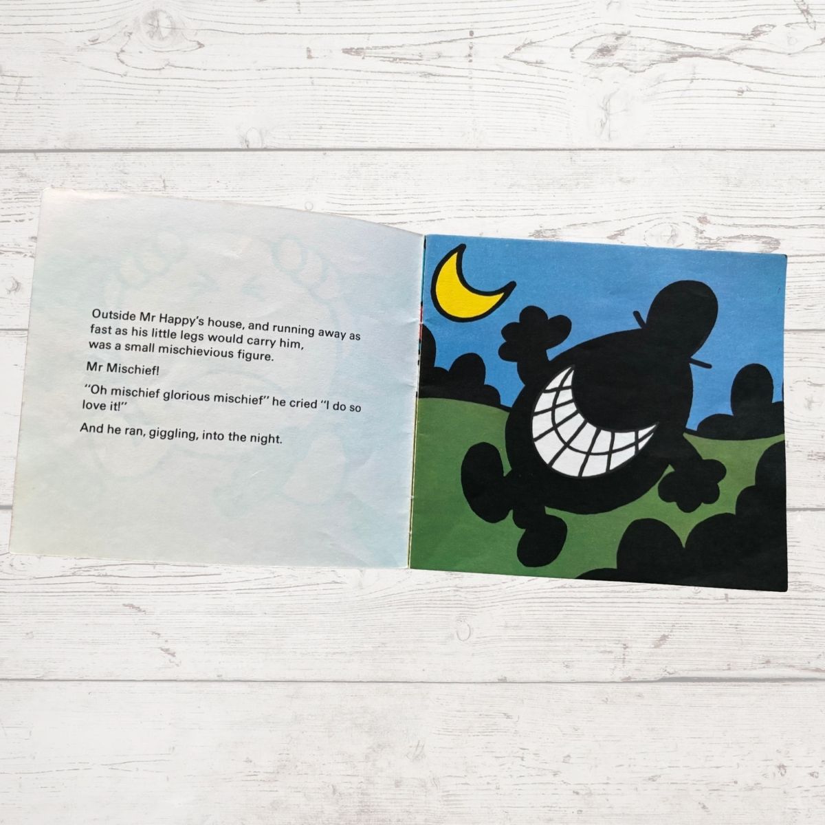 Open book with a silhouette of a character and moon on a blue sky background.