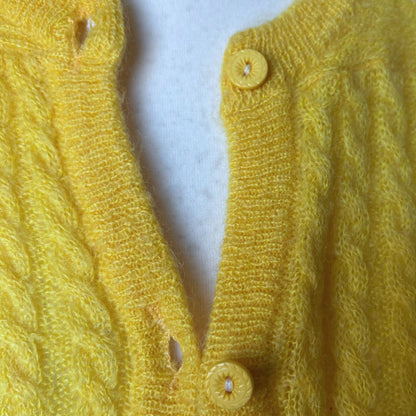 Close-up of a yellow knitted garment with buttons on a white background