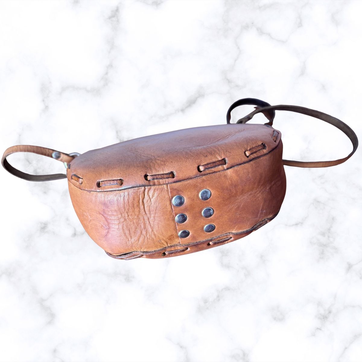 Tooled leather shoulder bag on a white background / base view with metal studs 