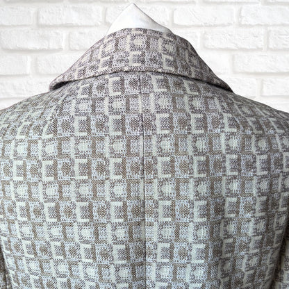 Patterned coat on a mannequin against a white brick wall background