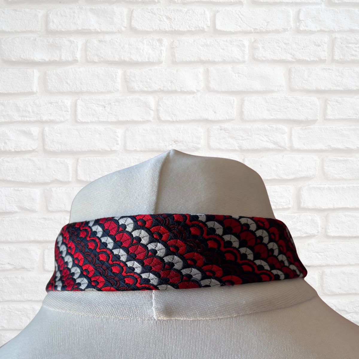 Patterned tie  on a mannequin against a white brick wall background