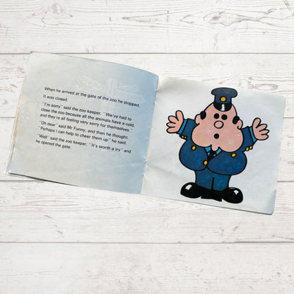 Open book with a cartoon character zoo keeper on a wooden surface