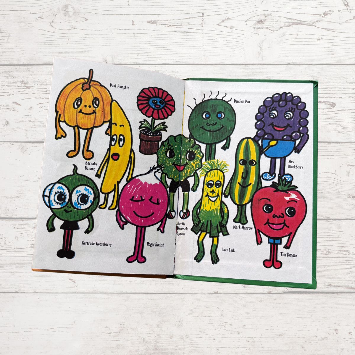 Open book with colorful illustrations of vegetables on a wooden surface
