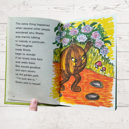 Open book with a colorful illustration of a character in a garden on a wooden surface.