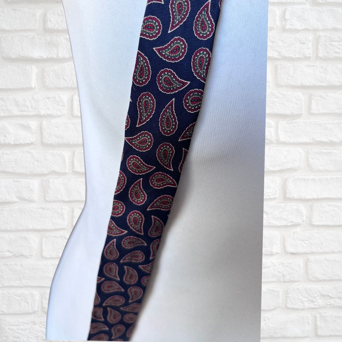 Navy and Red Paisley Silk Vintage Tie On a white brick background - close up 