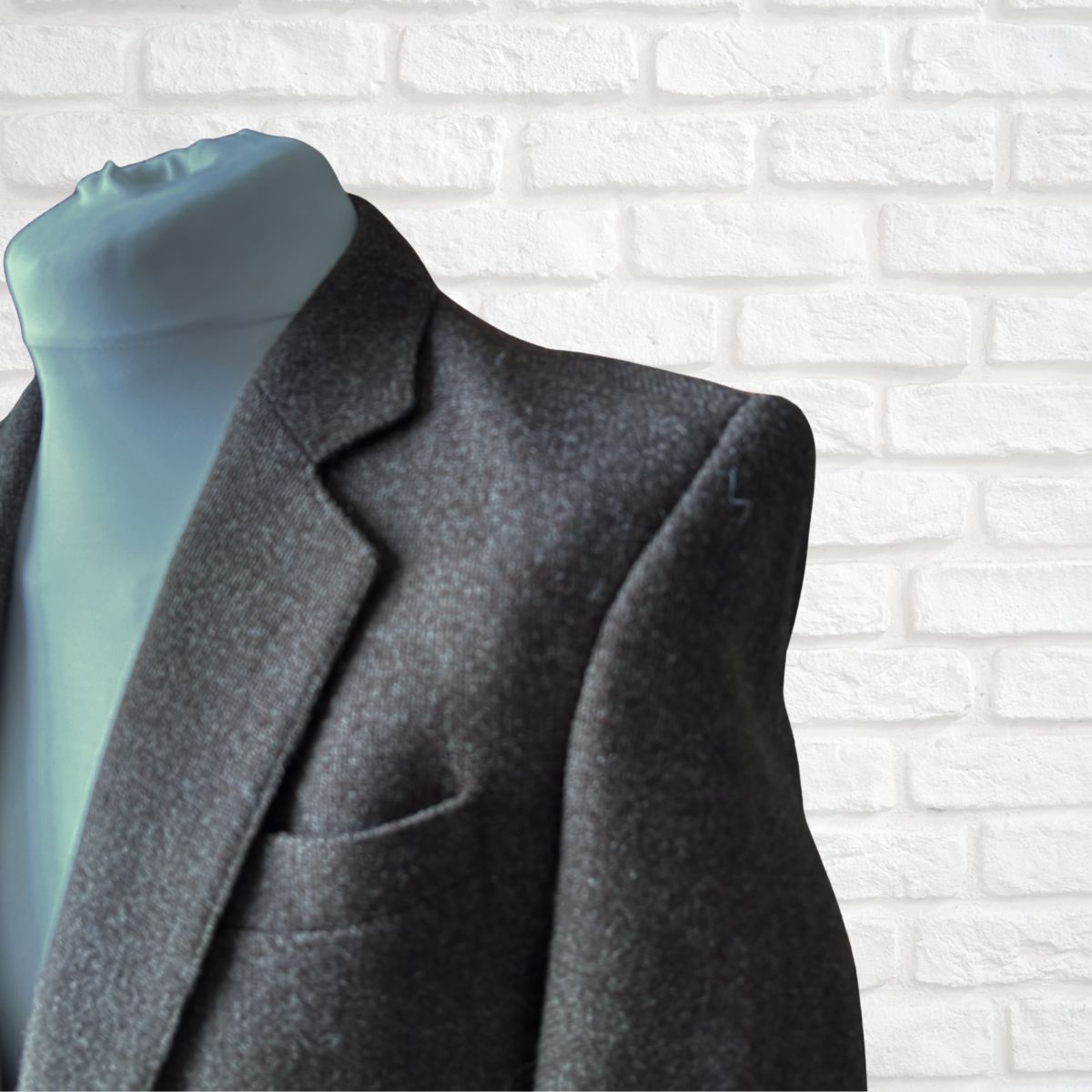 Brown jacket  on a mannequin with a white brick wall background