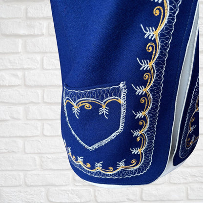 Blue fabric with white and gold embroidery on a white brick wall background