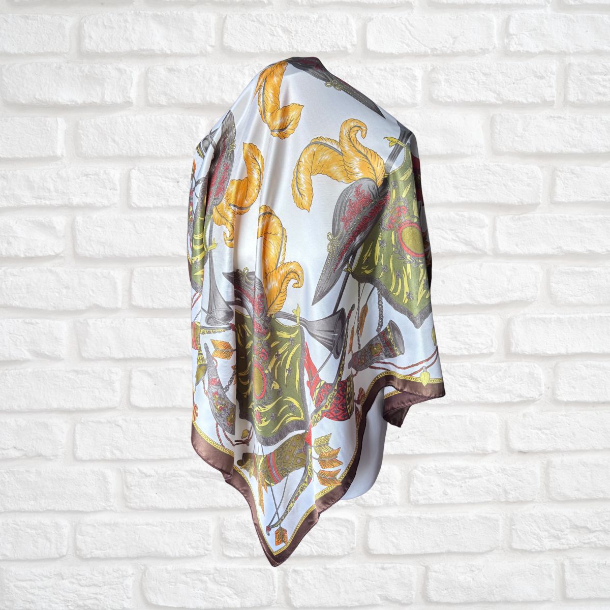 Decorative scarf with floral pattern draped over a white brick wall