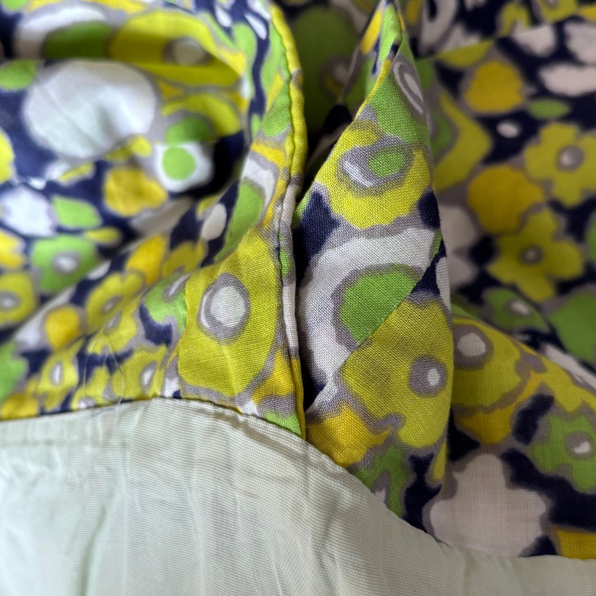 Close-up of a floral-patterned fabric with green, yellow, and purple colors.
