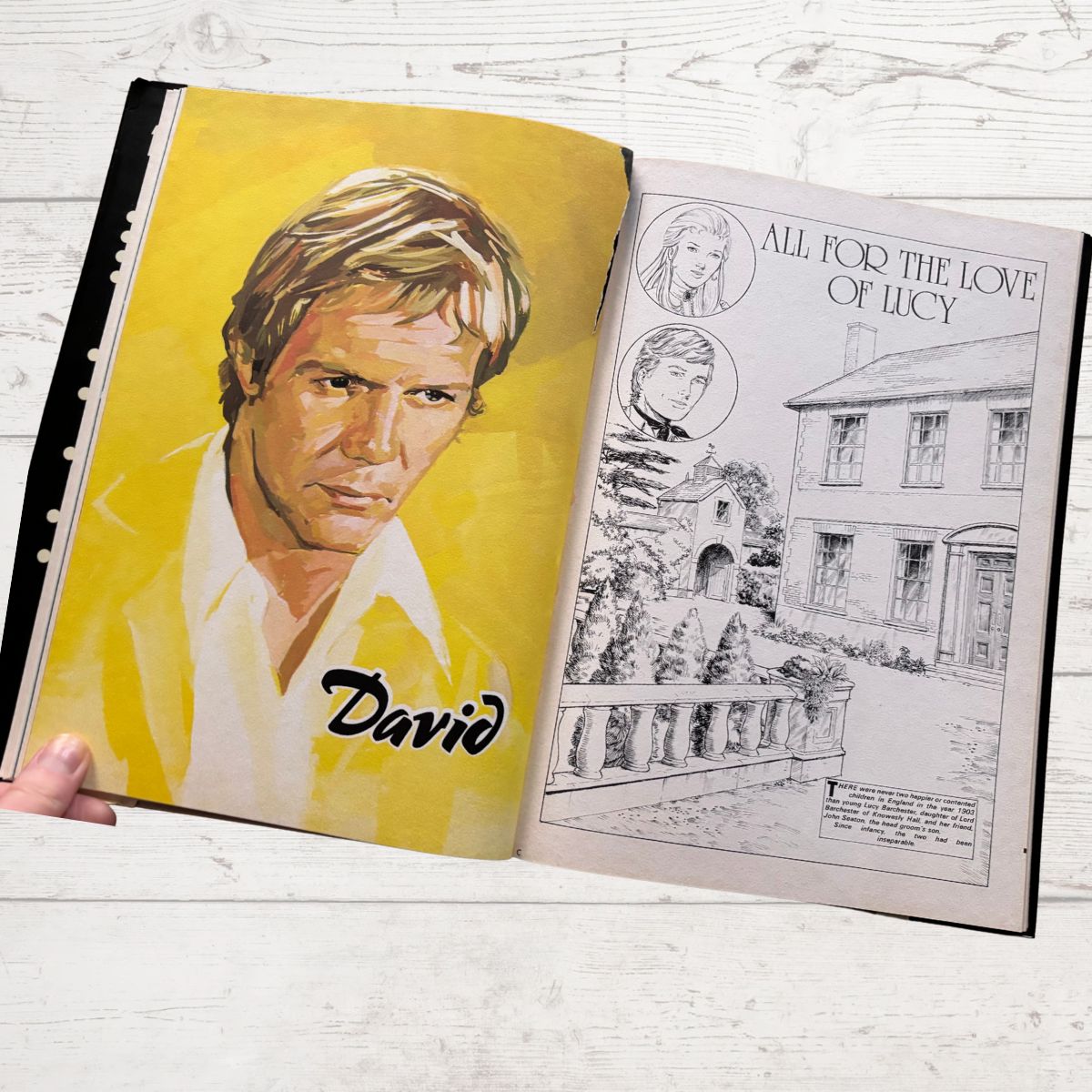 Open book with a portrait of a man on one page and black and white illustration on the other, on a light wooden surface.