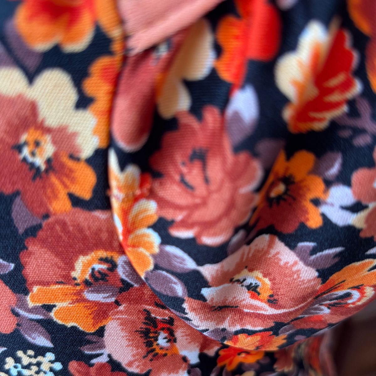 Close-up of a fix on floral fabric dress with orange flowers on a dark background 