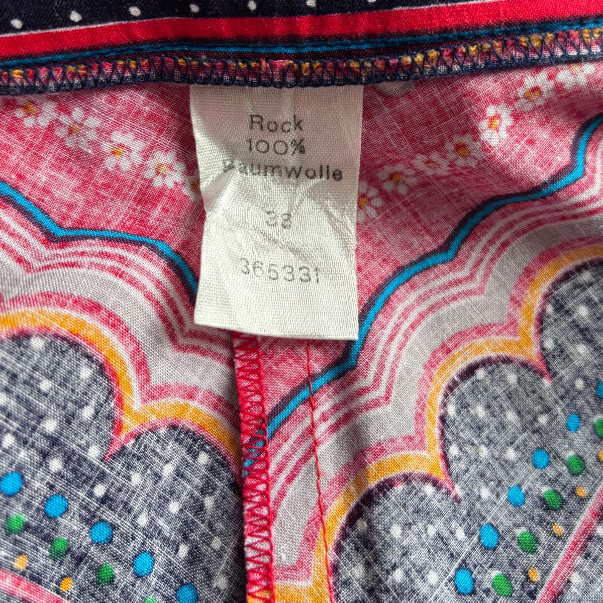 Close-up of skirt fabric with colourful patterns and a label on a red background
